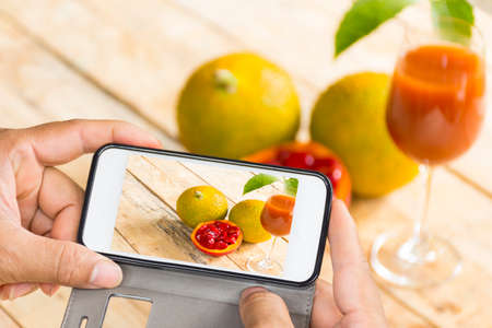 Man taking photo of fruit or green baby jackfruit by smartphone.fruit for health and herb or clean food.Top view.の写真素材