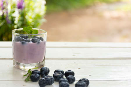 Yogurt Blue Berry and fresh berry on  wooden white table on background outdoor view.Close up.の写真素材