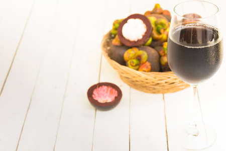 Mangoteen and mangoteen slice in the basket with juice from rind on wooden white background.Top view and zoom in.の写真素材