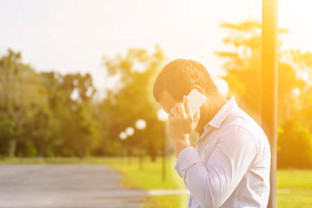Man talking mobile with background nature outdoor and sunshine view.の写真素材