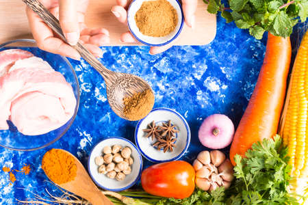 Background cooking or Woman cooking with ingredients spoon in her hands on background vegetable on blue table.Dark tone and Top view.の写真素材