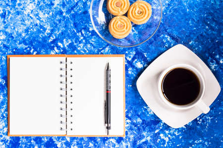 Background coffee cup and cookies  and notebook with pencil on sky table or dark tone background.Top view.の写真素材