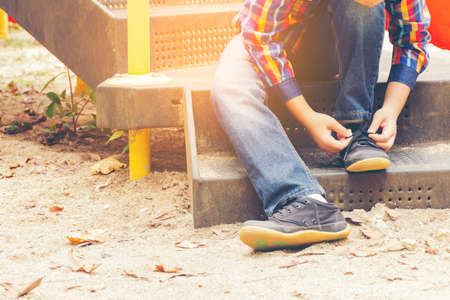 Child   tying shoes in the playground.Zoom in.001の写真素材