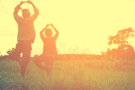 Family are exercising or yoga with mountain view,Or Father and son are activities in the meadow and sunshine view.の写真素材