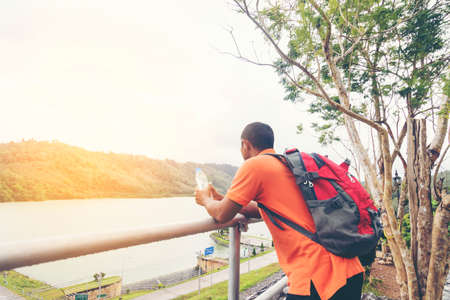 Man Asian backpack holding water bottle and looking nature view.の写真素材