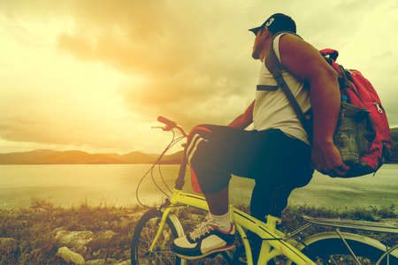 Man Asian backpack with his bike and sunshine view.の写真素材