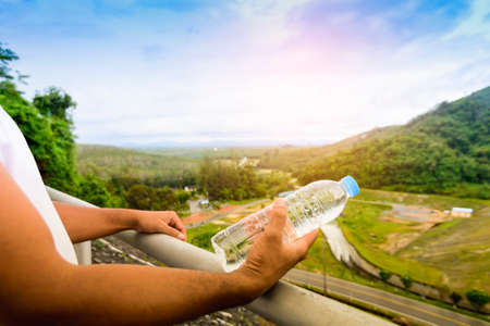 Hand holding water bottle and background of nature view.の写真素材