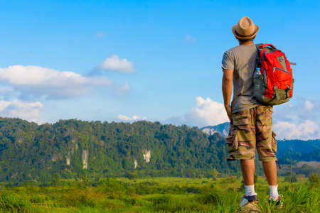 Man Asian backpack standing on the rock and looking mountain background.Back of manの写真素材