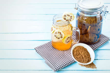 Noni juice and noni powder with noni fermented on brown checkered fabricの写真素材