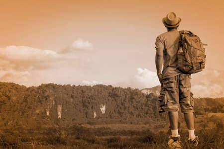 Man Asian backpack standing on the rock and looking mountain background.Back of man.Toneの写真素材