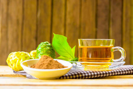 Hot herbal noni,Noni herbal juice with noni fruit and noni powder on wooden background.の写真素材