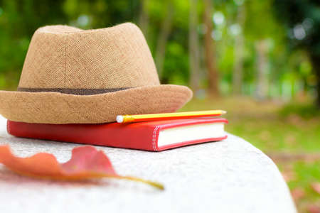 Concept holiday,Notebook and pencil with hat on white table in public park.の写真素材