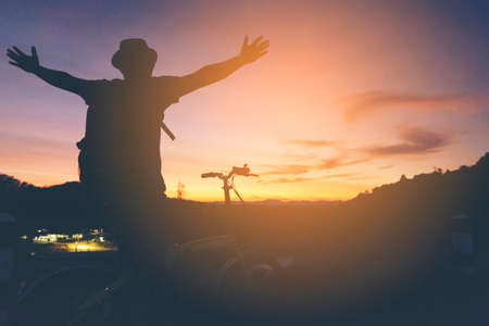 Silhouette of man hipster is happy with bike  and  sunshine   view.の写真素材
