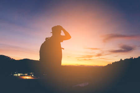 Silhouette of man hipster backpack looking sunshine  and mountain view.の写真素材