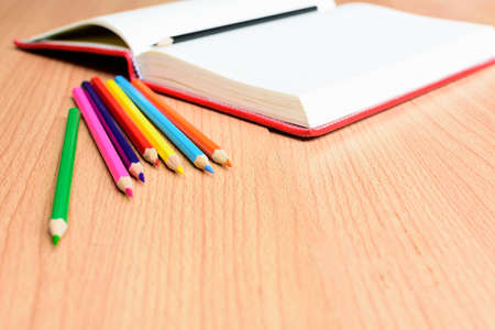 Open notebook with color pencil on wooden table.Close up