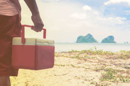 Hand  of man red Ice box  with background the beach and island view.の写真素材