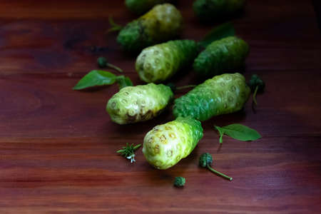 Noni fruit and leaves on red and brown wooden right corner.1の写真素材