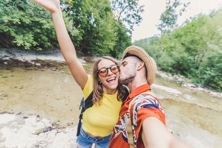 Excited couple is taking an happy selfie on excursion in a forest at vacationの写真素材