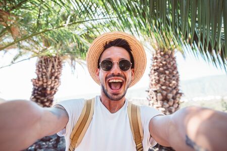 Handsome man with backpack taking a holiday selfie at tropical islandの写真素材