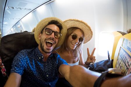 Crazy and happy couple take selfie on the airplane during flight. Concept about travel, lifestyle and happinessの写真素材
