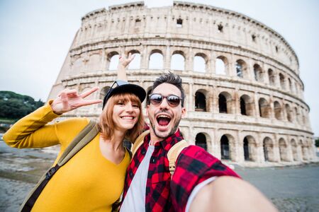 Happy couple of tourist smiling and taking a selfie at the Colosseum in Rome.の写真素材