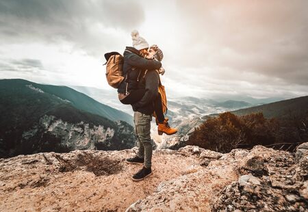 Couple of hikers in love have a romantic kiss on the top of a mountain at winter. Young people are kissing in the nature.の写真素材