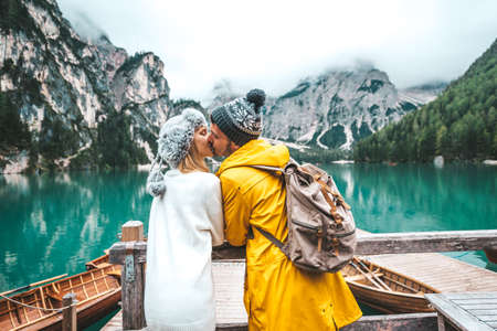 Romantic kiss of a couple of adults visiting an alpine lake at Braies Italy. Tourist in love spending loving moments together at autumn mountains. Couple, wanderlust and travel concept.の写真素材