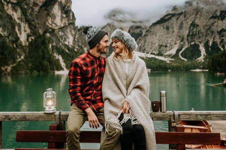 Portrait of a romantic couple of adults visiting an alpine lake at Braies Italy at winter. Tourist...
