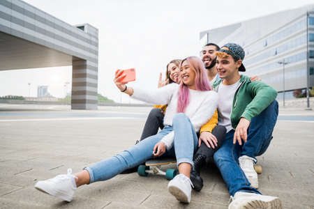Multiracial friends taking selfie at skate park - Happy youth and friendship concept with young millenial people having fun together in urban city areaの写真素材