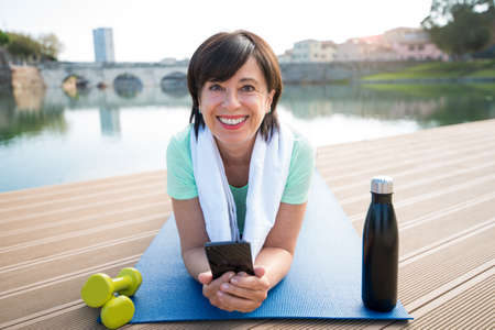 Senior woman training work out outdoor. Mature woman using fitness app doing sport. Senior people, fitness and technology concept.の写真素材