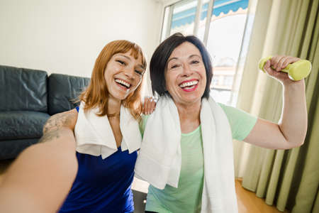 Happy mother and daughter taking a selfie workout gym at home during quarantine. Concept about people, family, gym at home, sport.の写真素材