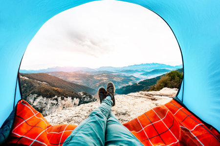 Man lying in a tent with the view of mountains and sunset - Sport, travel and lifestyle concept.の写真素材