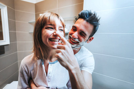 Young couple having fun playing with shaving foam in the bathroomの写真素材