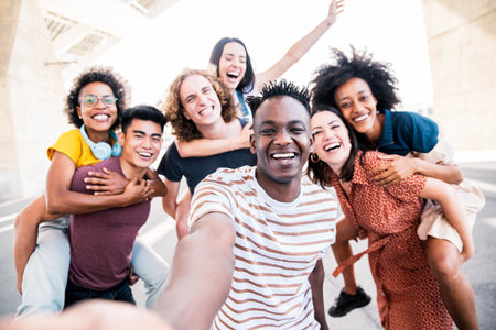 Multicultural happy friends having fun taking group selfie portrait on city streetの写真素材