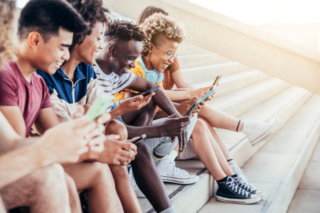 Diverse teenage students using digital smart mobile phones on college campusの写真素材