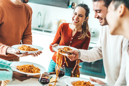 Happy group of friends eating pasta at home dinner party