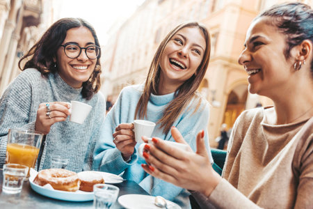 Three young women enjoying breakfast drinking coffee sitting at bar cafeteriaの写真素材
