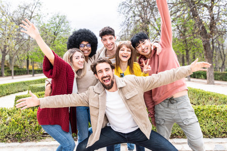 Young people with hands up laughing together at camera