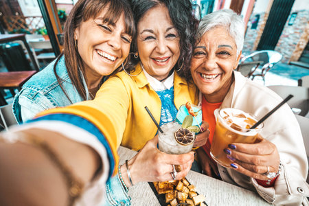 Happy senior women drinking cocktail glasses sitting at bar table