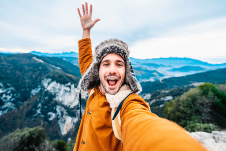 Young man taking a selfie with mobile smart phone hiking mountains - Happy smiling guy looking at cameraの写真素材