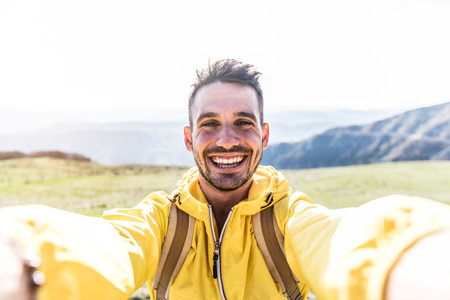 Happy hiker taking a selfie on the top of a mountain - Smiling man looking camera - Handsome male face outdoorの写真素材