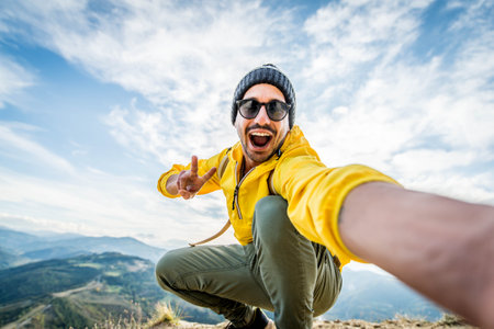 Young hiker man taking selfie portrait on the top of mountain - Happy guy smiling at cameraの写真素材