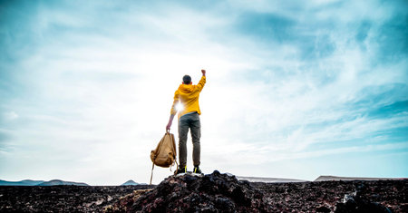 Successful man standing on the top of the mountain at sunset - Hiker with backpack extreme climbingの写真素材