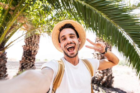 Young man with backpack taking selfie portrait on exotic beach -Smiling happy guy enjoying summer holidaysの写真素材