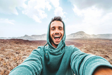 Handsome man taking selfie photo with smart mobile phone device outside - Cheerful climber hiking mountainsの写真素材