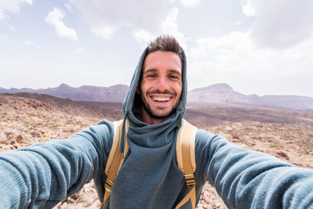 Handsome hiker taking a selfie hiking a mountain using his smartphoneの写真素材