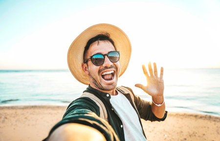 Handsome young man taking selfie with smart mobile phone device at the beach - Happy tourist taking selfieの写真素材