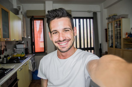 Photo of handsome man taking a selfie at home smiling on the cameraの写真素材