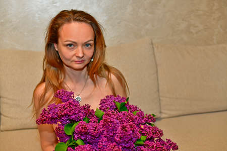 Adult woman with a large bouquet of lilacs.の写真素材