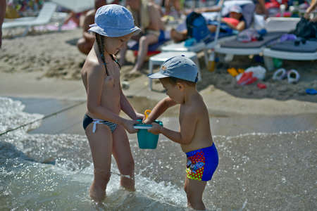 Children girls and boy play on the black sea shore in the sand.の写真素材